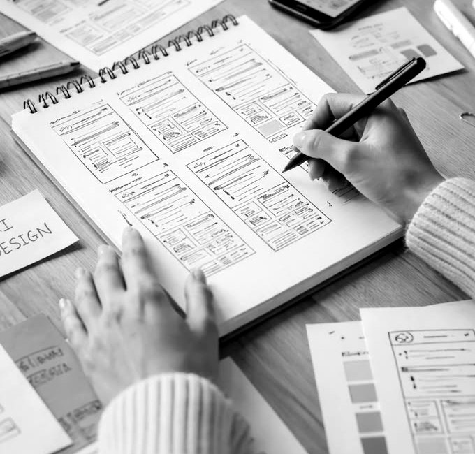 Designer sketching website wireframes in a spiral sketchbook